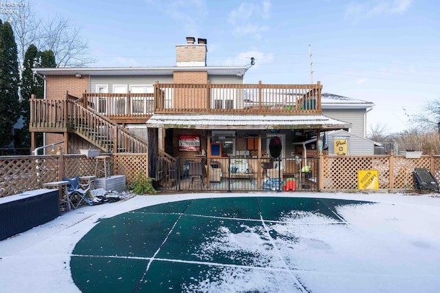 snow covered back of property featuring a deck