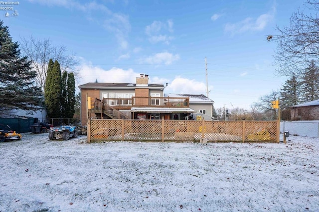 snow covered back of property with a deck