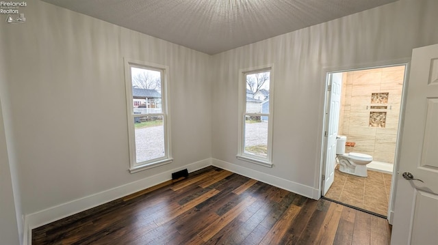 spare room featuring dark hardwood / wood-style floors and a textured ceiling