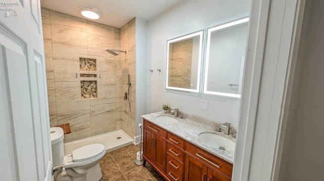 bathroom with tiled shower, tile patterned floors, vanity, and toilet