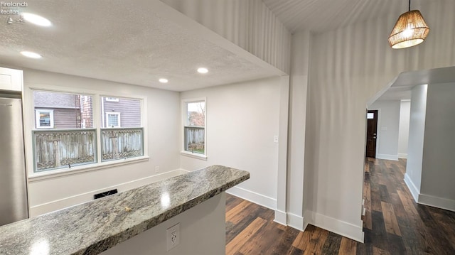 kitchen featuring decorative light fixtures, stainless steel fridge, dark wood-type flooring, and stone counters