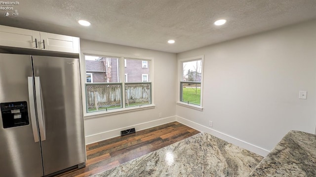 kitchen with light stone countertops, a textured ceiling, white cabinets, stainless steel fridge with ice dispenser, and dark hardwood / wood-style floors