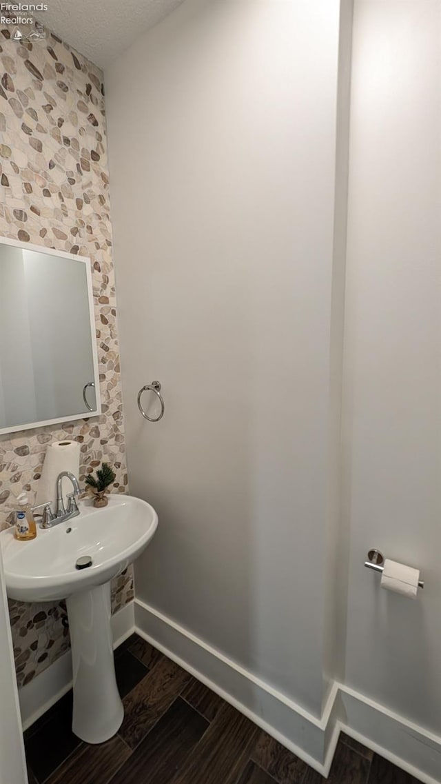 bathroom featuring wood-type flooring and a textured ceiling