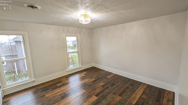 unfurnished room featuring a textured ceiling, dark wood-type flooring, and a wealth of natural light