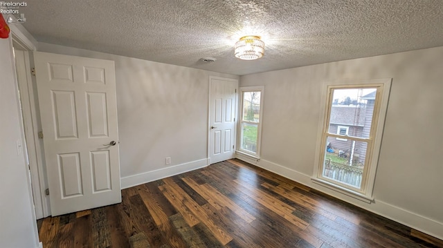 spare room featuring a textured ceiling and dark hardwood / wood-style floors