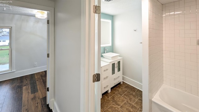 bathroom featuring sink, wood-type flooring, a textured ceiling, and tiled shower / bath