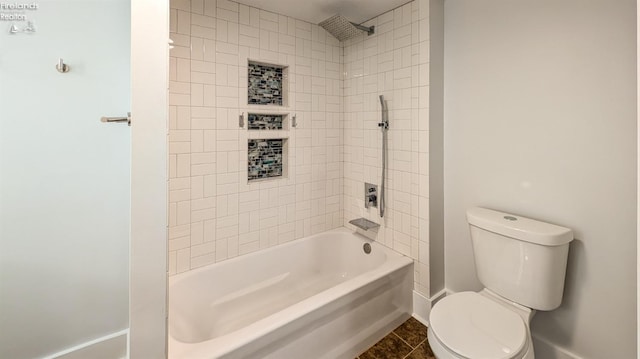 bathroom with tile patterned flooring, tiled shower / bath combo, and toilet