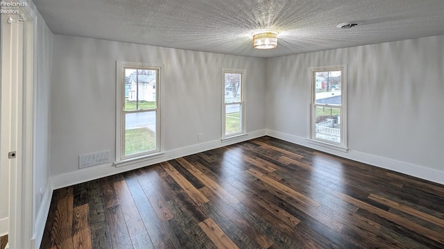 spare room featuring dark hardwood / wood-style flooring, a textured ceiling, and a chandelier