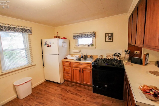 kitchen featuring hardwood / wood-style floors, plenty of natural light, white fridge, and black range with electric cooktop