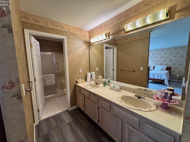 bathroom with hardwood / wood-style floors, vanity, a shower with door, and a textured ceiling