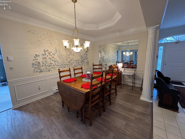 dining room with a notable chandelier, wood-type flooring, ornamental molding, and ornate columns