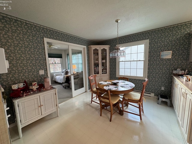 dining space featuring a textured ceiling, ceiling fan, and a baseboard heating unit