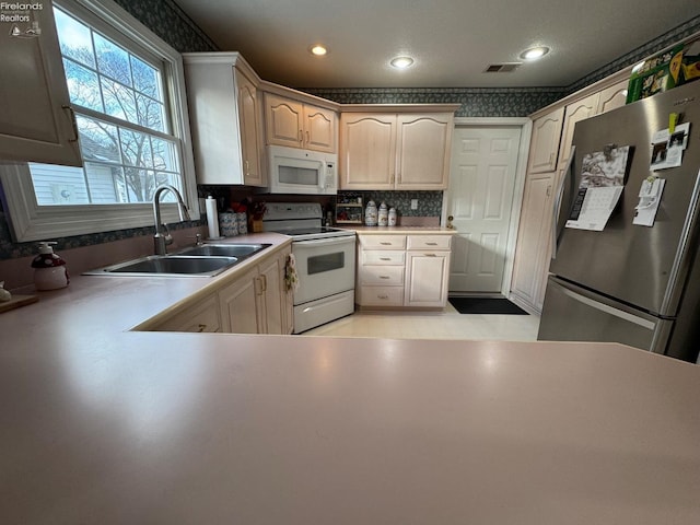 kitchen featuring backsplash, sink, light tile patterned floors, and white appliances