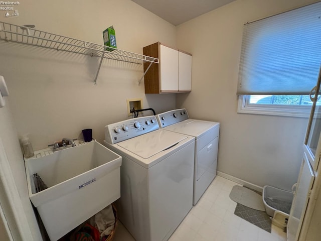 clothes washing area featuring washer and dryer, sink, and cabinets