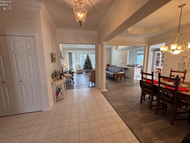 entryway with decorative columns, hardwood / wood-style flooring, ornamental molding, and an inviting chandelier