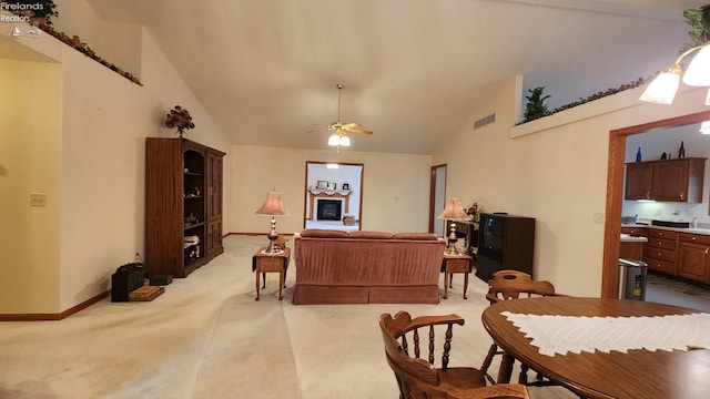 carpeted living room with ceiling fan and vaulted ceiling