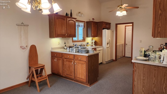 kitchen featuring dark colored carpet, lofted ceiling, washer / dryer, white appliances, and ceiling fan with notable chandelier