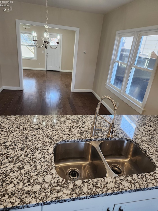 room details featuring pendant lighting, stone countertops, sink, a notable chandelier, and dark hardwood / wood-style flooring