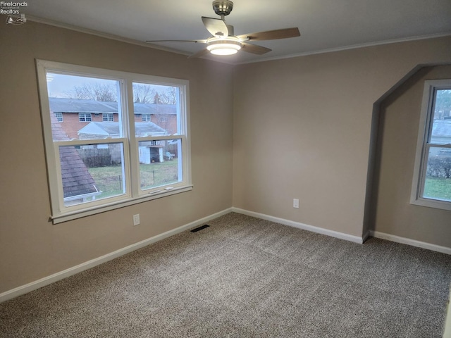 carpeted empty room with ceiling fan, a healthy amount of sunlight, and crown molding