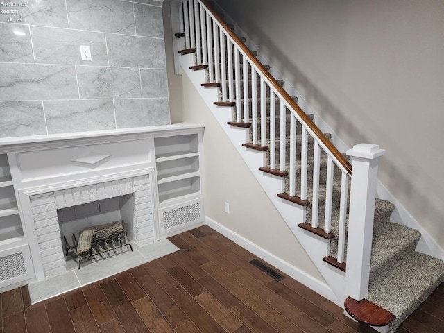 stairs with hardwood / wood-style floors and a tiled fireplace