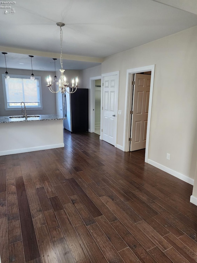 unfurnished dining area with sink, a chandelier, and dark hardwood / wood-style floors