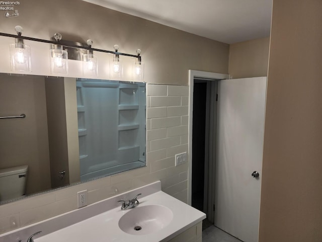 bathroom with vanity, tile walls, and toilet