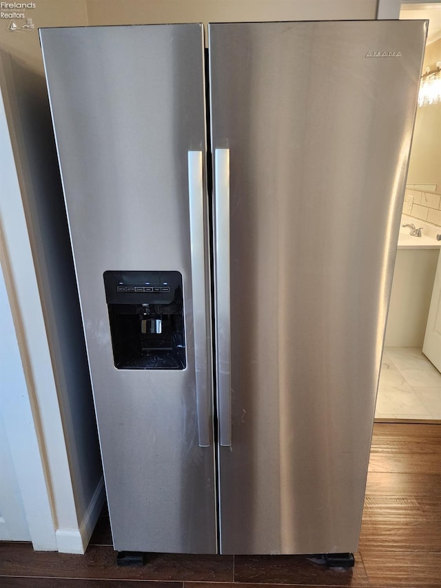 details featuring tasteful backsplash, hardwood / wood-style floors, and stainless steel refrigerator with ice dispenser