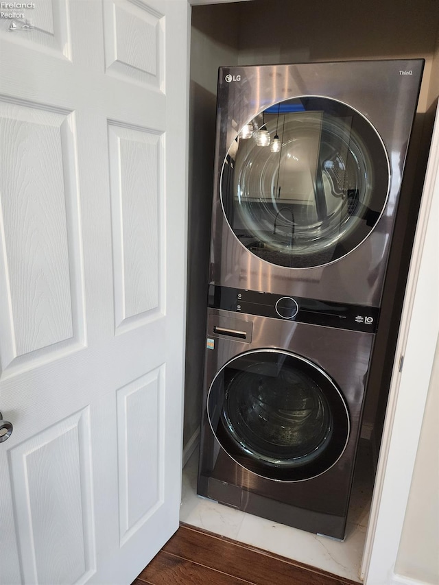 washroom featuring dark hardwood / wood-style floors and stacked washer / drying machine