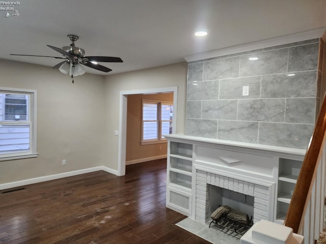 unfurnished living room featuring ceiling fan, a fireplace, and dark wood-type flooring