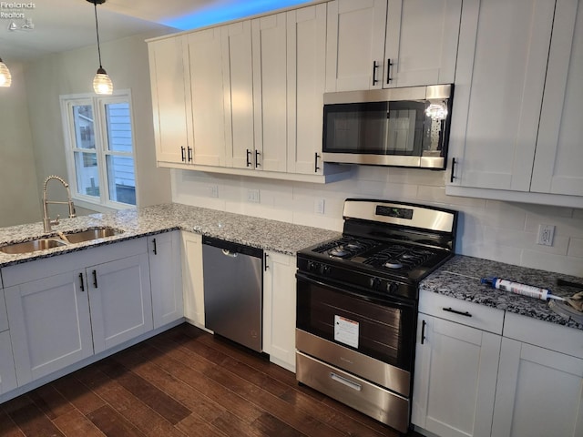 kitchen featuring pendant lighting, dark wood-type flooring, sink, appliances with stainless steel finishes, and white cabinetry