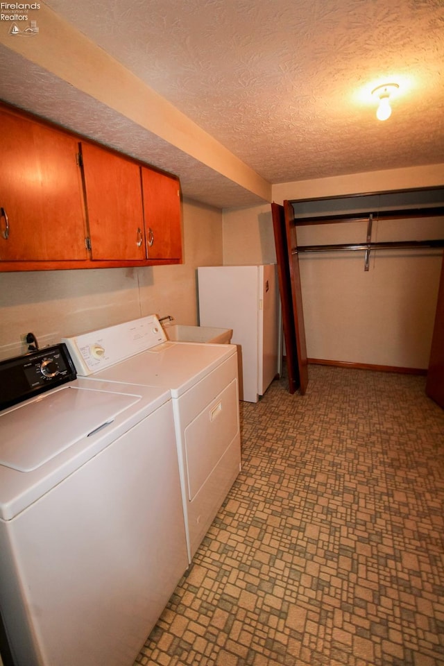 laundry room featuring washer and clothes dryer, cabinets, and a textured ceiling