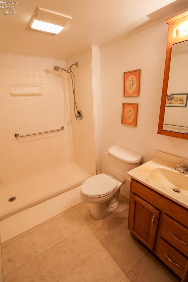 bathroom with a tile shower, tile patterned flooring, vanity, and toilet