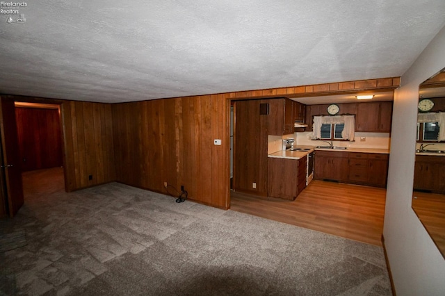 kitchen featuring electric range, sink, light hardwood / wood-style floors, and a textured ceiling