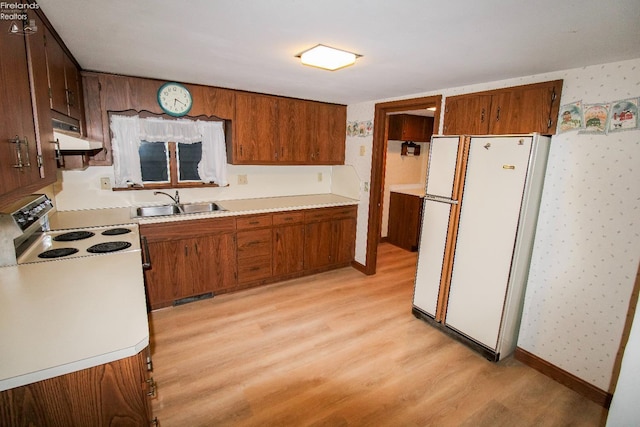 kitchen featuring light wood-type flooring, white appliances, and sink