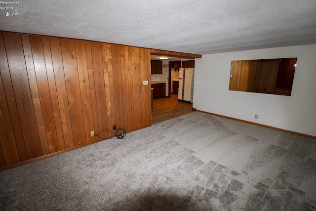 carpeted empty room with a textured ceiling and wooden walls