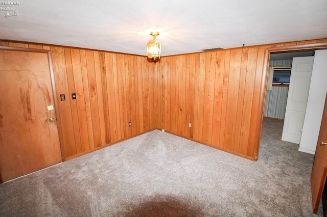 spare room featuring wood walls and carpet floors