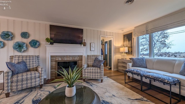 living room with a stone fireplace, dark hardwood / wood-style floors, and ornamental molding