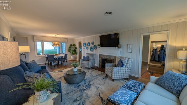 living room featuring hardwood / wood-style floors, a stone fireplace, and crown molding