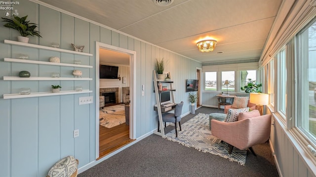 living area featuring crown molding, carpet, and a brick fireplace