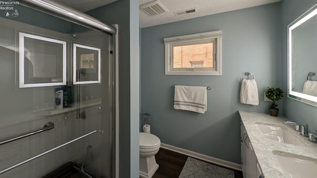 bathroom featuring vanity, toilet, a textured ceiling, an enclosed shower, and wood-type flooring