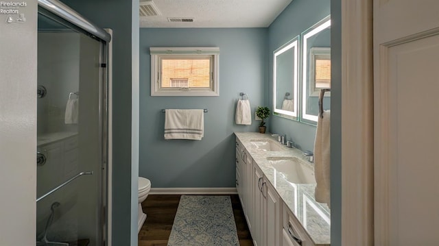 bathroom featuring vanity, a textured ceiling, wood-type flooring, toilet, and a shower with shower door