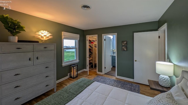 bedroom featuring a closet, light hardwood / wood-style floors, a spacious closet, and ensuite bath