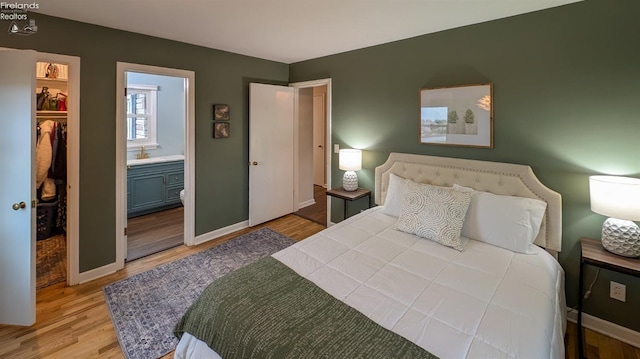 bedroom featuring ensuite bath, a closet, and light wood-type flooring