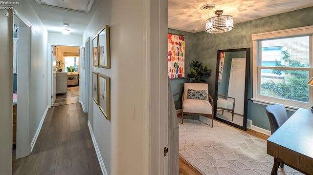 hall with wood-type flooring and an inviting chandelier