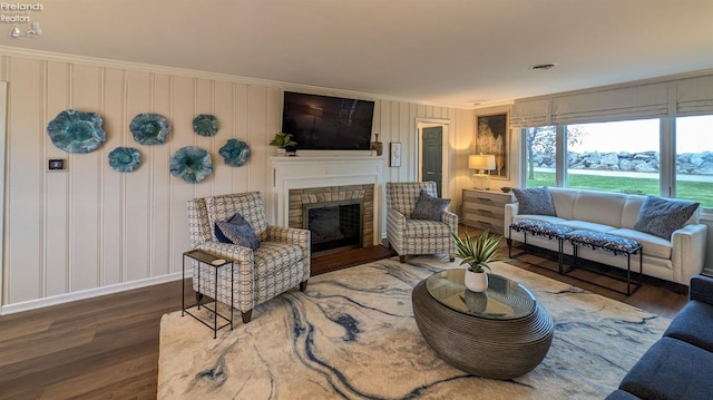 living room featuring dark hardwood / wood-style flooring, ornamental molding, and a fireplace