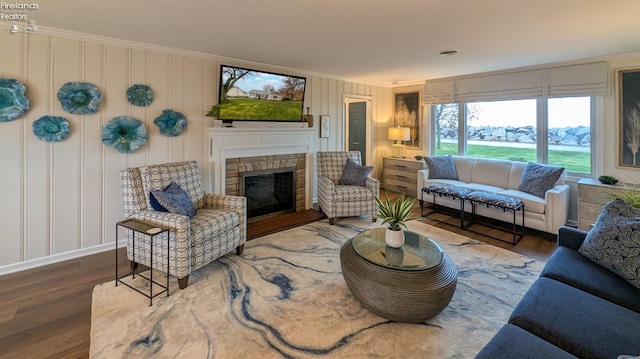 living room with dark hardwood / wood-style flooring, ornamental molding, and a fireplace