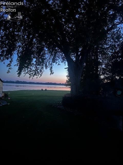 yard at dusk featuring a water view