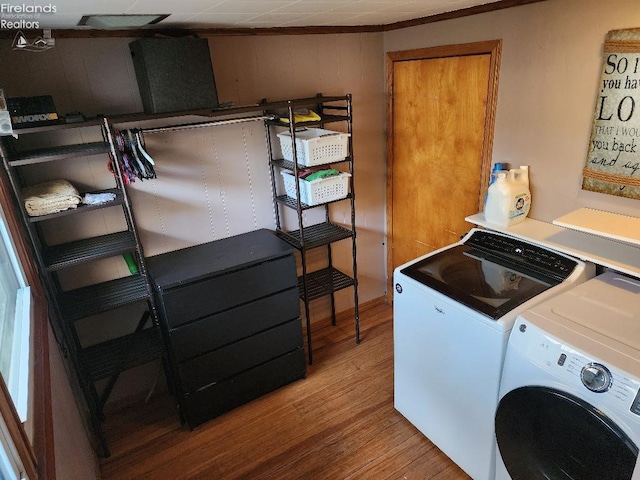 clothes washing area with hardwood / wood-style floors and washing machine and clothes dryer