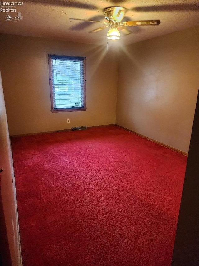 empty room with carpet flooring, ceiling fan, and a textured ceiling