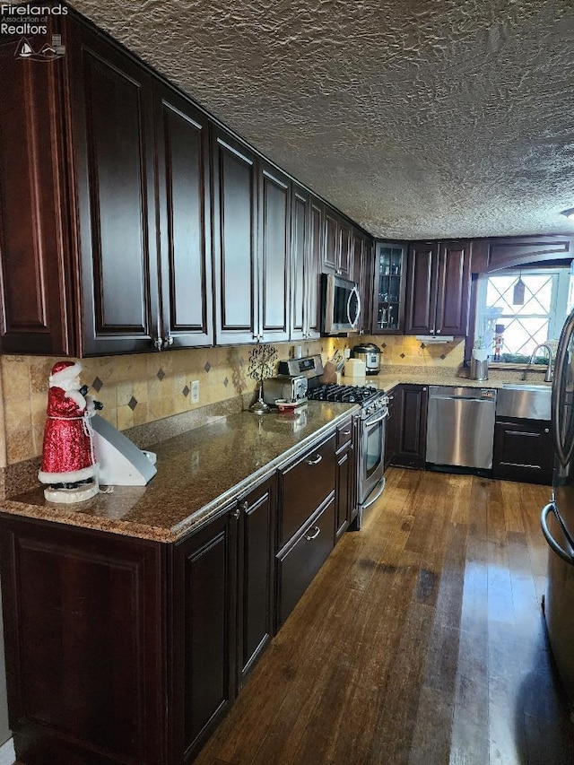 kitchen with dark brown cabinets, a textured ceiling, stainless steel appliances, and dark wood-type flooring